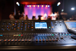 Installations live theater concert show sound video music control console with scene lights background. sound engineer mixer soundboard equipment with many knobs, buttons, faders, equalizer screen and light